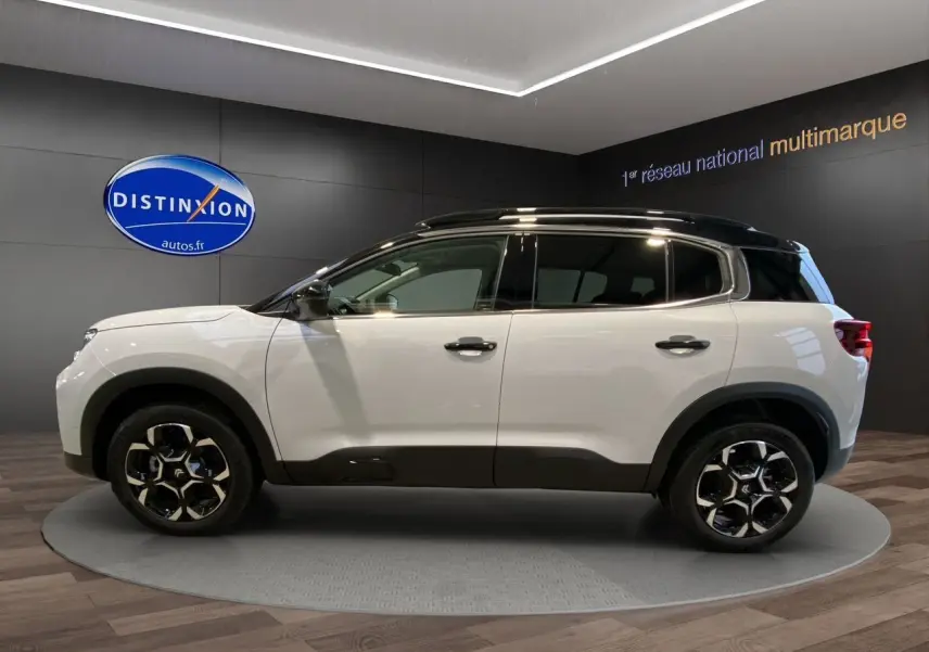 Profil côté gauche du Citroën C5 Aircross 2024 blanc et noir avec jantes noires et toit contrasté en showroom.
