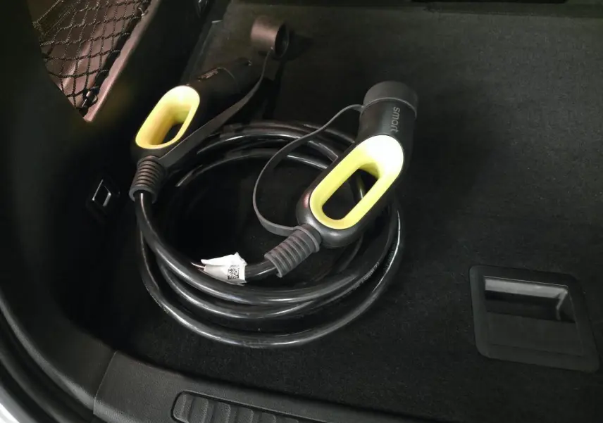 Câble de recharge électrique noir avec poignées jaunes dans le coffre d'une Smart #1 blanc 2024.