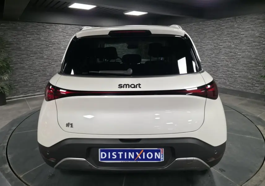 Vue arrière d'une Smart #1 blanche électrique 2024 avec feux arrière reliés par une bande lumineuse rouge.