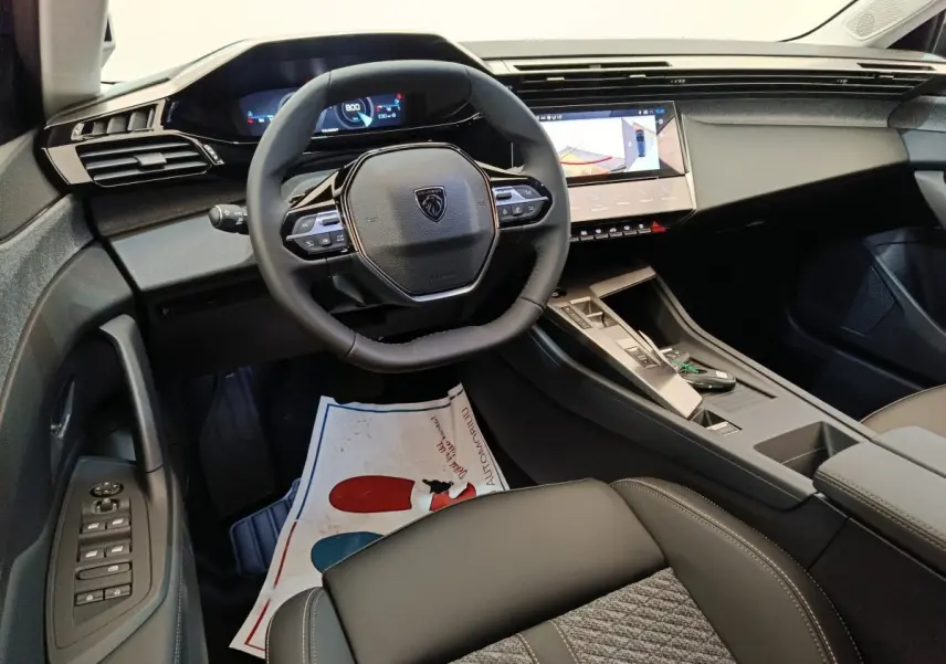 Vue intérieure avant droite du Peugeot 308 2026 avec volant cuir multifonctions et écran tactile central.