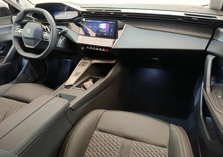 Vue intérieure côté conducteur de la Peugeot 308 2026 gris foncé, avec volant cuir multifonctions et écran tactile central.