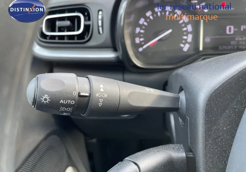 Gros plan sur la manette d'éclairage à gauche du volant dans l'habitacle d'une Citroën C3 gris platinium 2023.