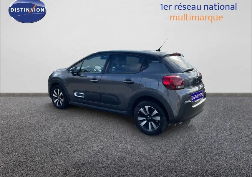 Citroën C3 gris platinium métal vue 3/4 arrière côté gauche avec jantes bi-ton et protections latérales blanches.