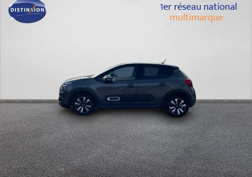 Profil côté gauche d'une Citroën C3 2023 gris platinium métallisé avec jantes bi-ton et protections latérales blanches.