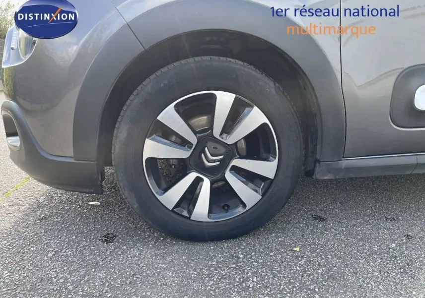 Gros plan sur la roue avant gauche d'une Citroën C3 gris platinium métal, mettant en valeur la jante bi-ton moderne.