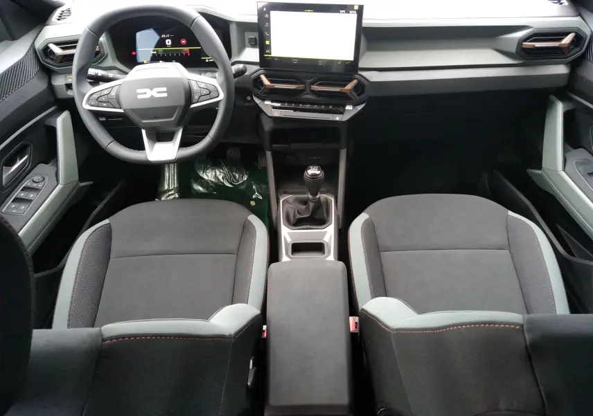 Vue intérieure avant du Dacia Bigster gris schiste, avec volant multifonction, écran tactile et levier de vitesses manuel.
