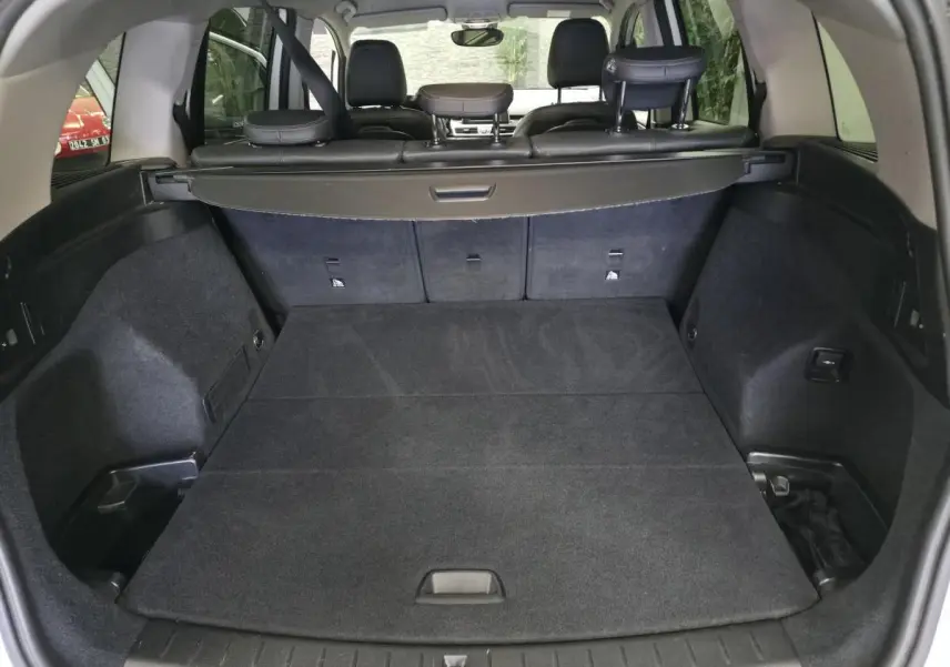 Coffre spacieux de BMW Série 2 Gran Tourer blanc, vue arrière avec banquette rabattue et cache-bagages noir.