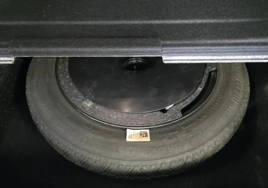 Gros plan sur la roue de secours dans le coffre d'une BMW Série 2 Gran Tourer blanche.