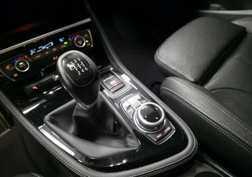 Gros plan sur la console centrale noire avec levier de vitesses manuelle et commandes iDrive d'une BMW Série 2 Gran Tourer.