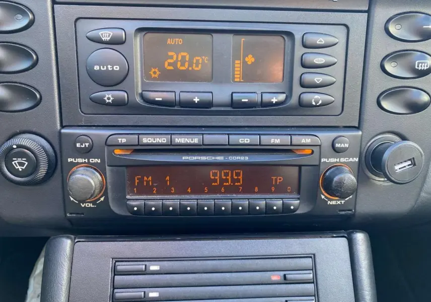 Tableau de bord de Porsche 911 Targa 2004 en gris foncé, vue rapprochée sur la radio et la climatisation digitale.