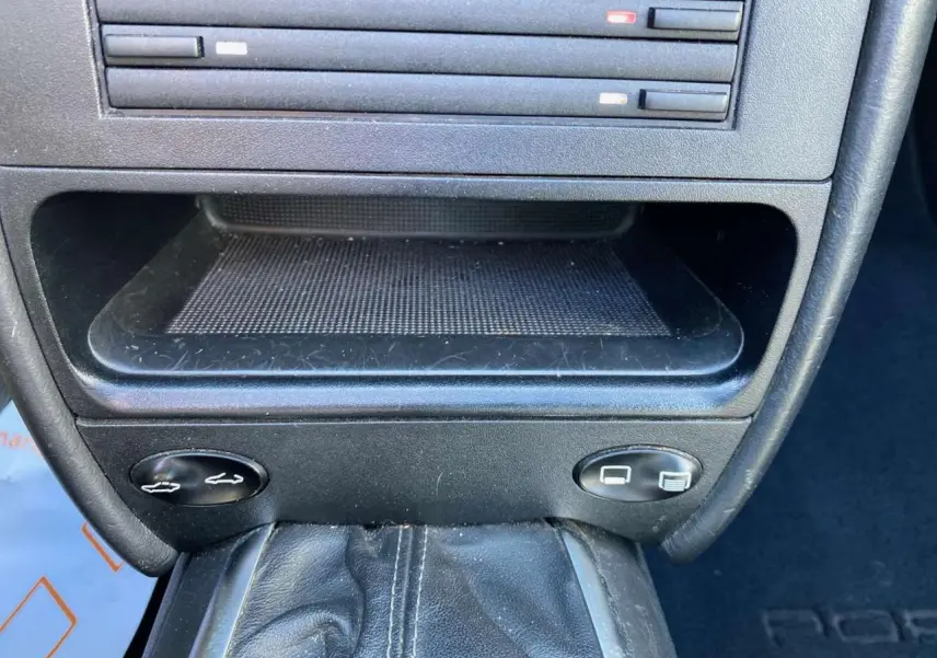 Gros plan sur la console centrale noire de la Porsche 911 Targa 3.6i 2004 avec levier de vitesses manuelle en cuir.