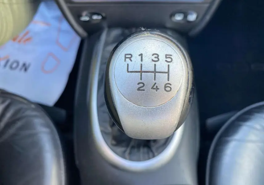 Gros plan sur le levier de vitesses manuel argenté dans l'habitacle noir d'une Porsche 911 Targa gris foncé de 2004.