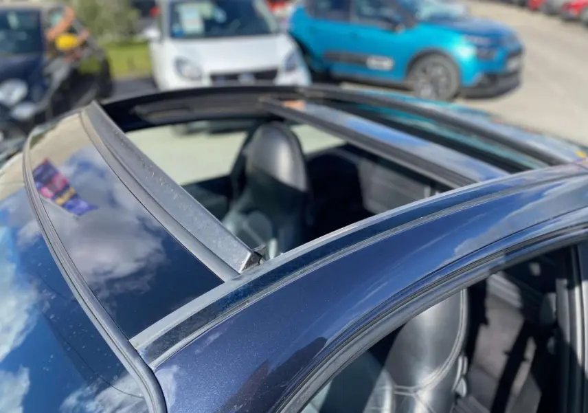 Vue rapprochée du toit ouvrant d'une Porsche 911 Targa 3.6i gris foncé de 2004, intérieur cuir noir visible.