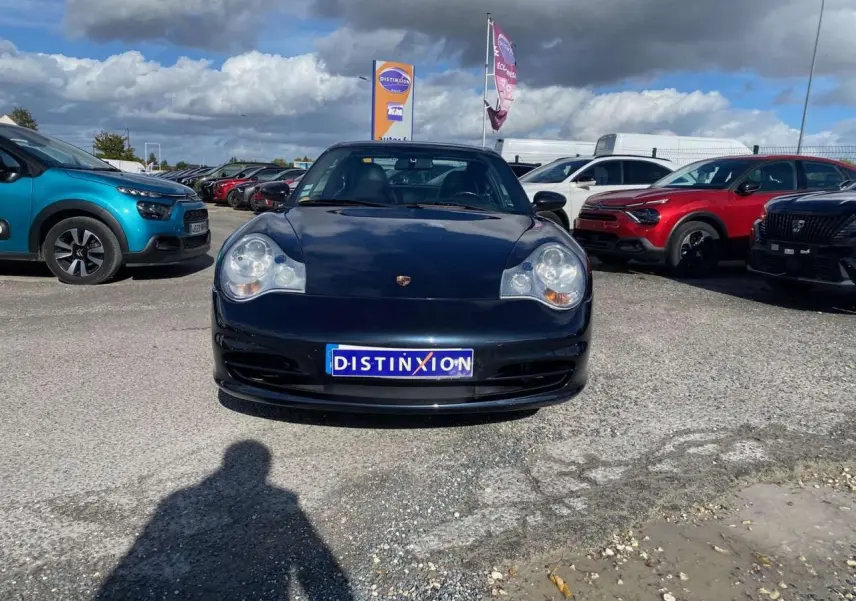 Vue avant d'une Porsche 911 Targa 3.6i 2004 gris foncé stationnée sur un parking ensoleillé.