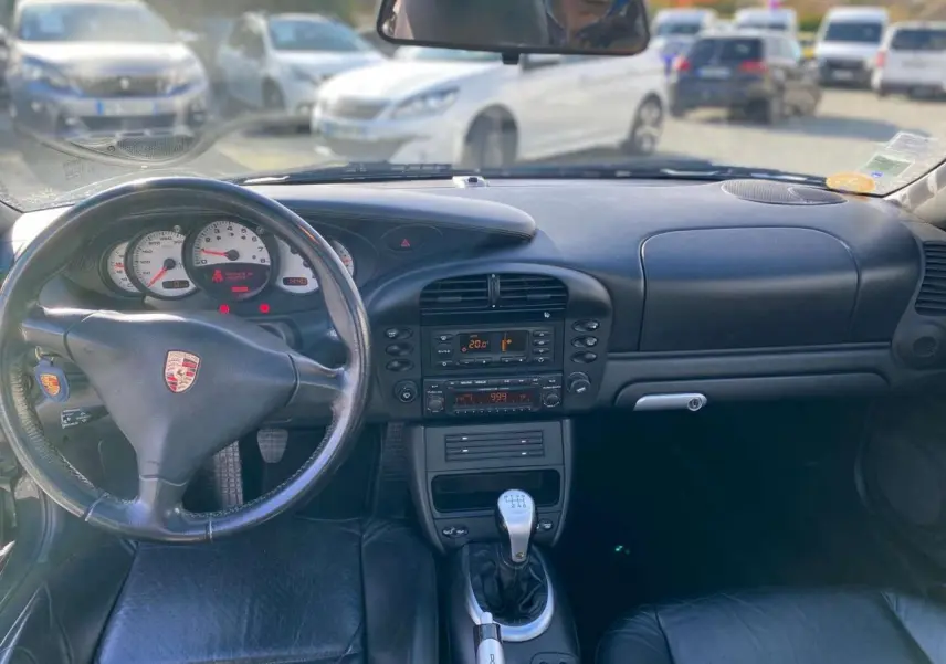 Vue intérieure avant du tableau de bord noir et volant Porsche avec levier de vitesse manuelle d'une 911 Targa gris foncé de 2004.