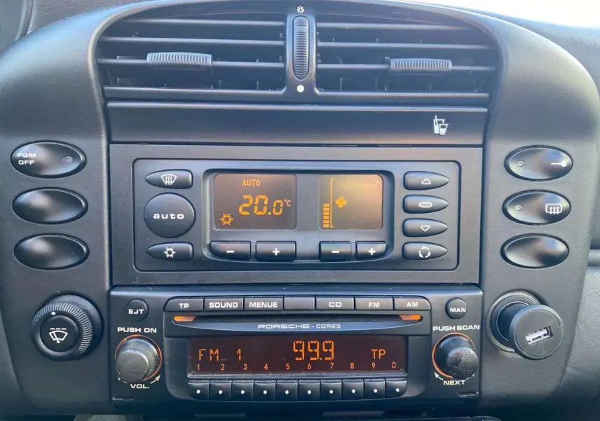 Vue rapprochée du tableau de bord noir du Porsche 911 Targa 3.6i 2004 avec commandes clim et radio d'origine.