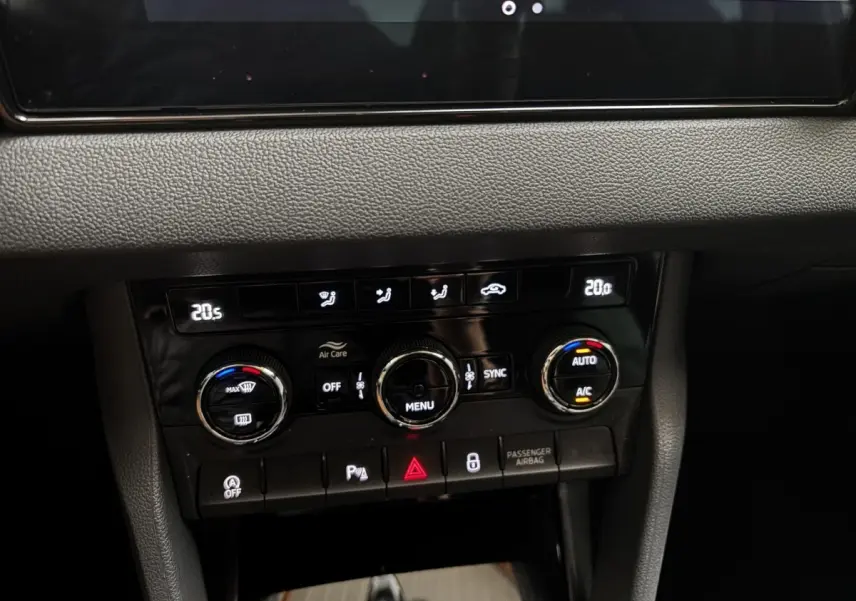 Gros plan sur la console centrale noire du Skoda Karoq 2025 montrant les commandes de climatisation digitale et boutons fonctionnels.