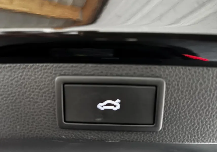 Bouton d'ouverture du coffre arrière sur tableau de bord intérieur du Skoda Karoq noir 2025.