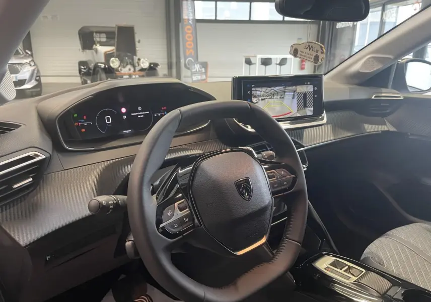Intérieur Peugeot 208 2025 vu côté conducteur, volant compact cuir et écran tactile avec caméra de recul.