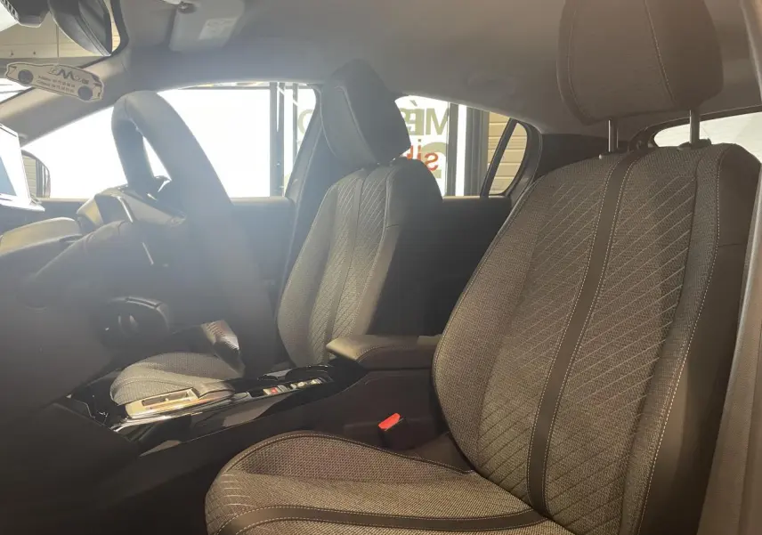Intérieur de la Peugeot 208 2025, vue côté droit sur les sièges avant en tissu gris avec surpiqûres Quartz.
