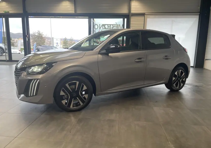 Peugeot 208 gris Artense vue de profil côté gauche en intérieur, avec jantes alliage bi-tons et feux LED 3 griffes.