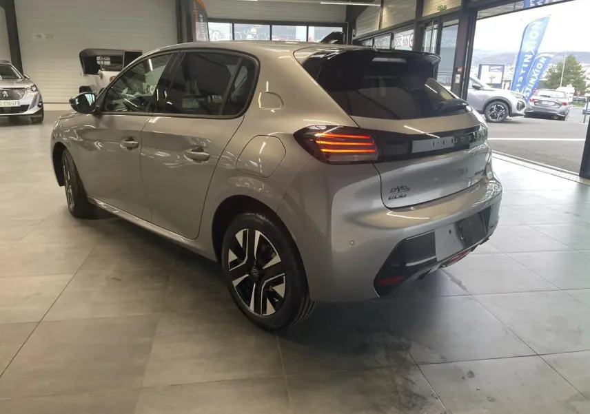 Peugeot 208 gris Artense vue 3/4 arrière droit en intérieur, feux arrière LED et jantes alliage bi-ton visibles