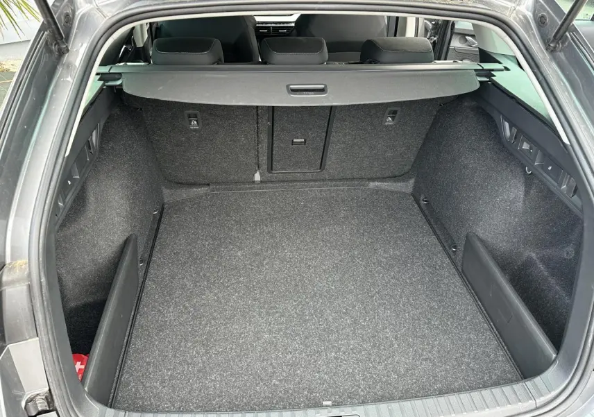Coffre ouvert vu de l'arrière d'une Skoda Octavia Combi gris graphite, montrant un espace de chargement propre et spacieux.