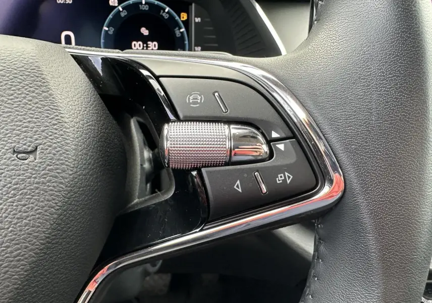 Gros plan sur les commandes chromées du volant cuir noir de la Skoda Octavia Combi 2024 avec tableau de bord numérique.