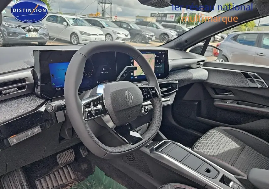 Vue intérieure avant droite de la Renault Clio VI gris rafale, volant multifonction et écran tactile large visibles.
