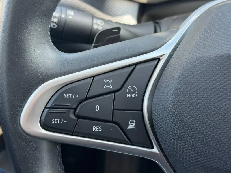 Gros plan sur les commandes au volant côté gauche du Renault Arkana gris métallisé 2025, avec boutons de régulateur et mode.