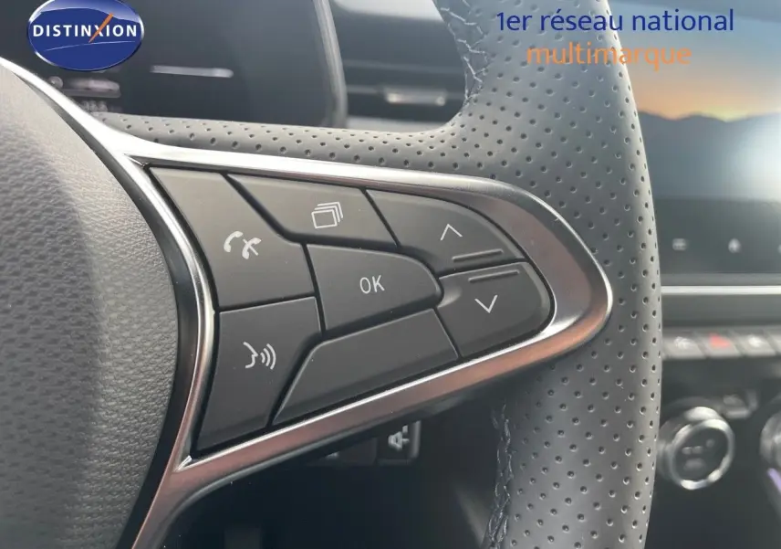 Gros plan sur les commandes du volant en cuir perforé de la Renault Clio TCE 90CH TECHNO bleu Iron Metal, intérieur moderne.