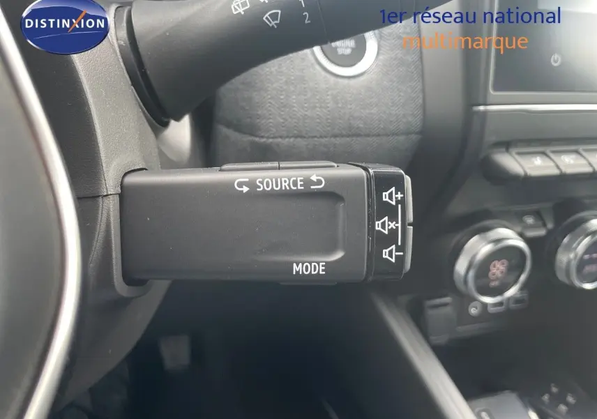 Commande multimédia au volant côté gauche de la Renault Clio TCe 90ch Techno 2025 avec tableau de bord noir et commandes climatiques visibles.