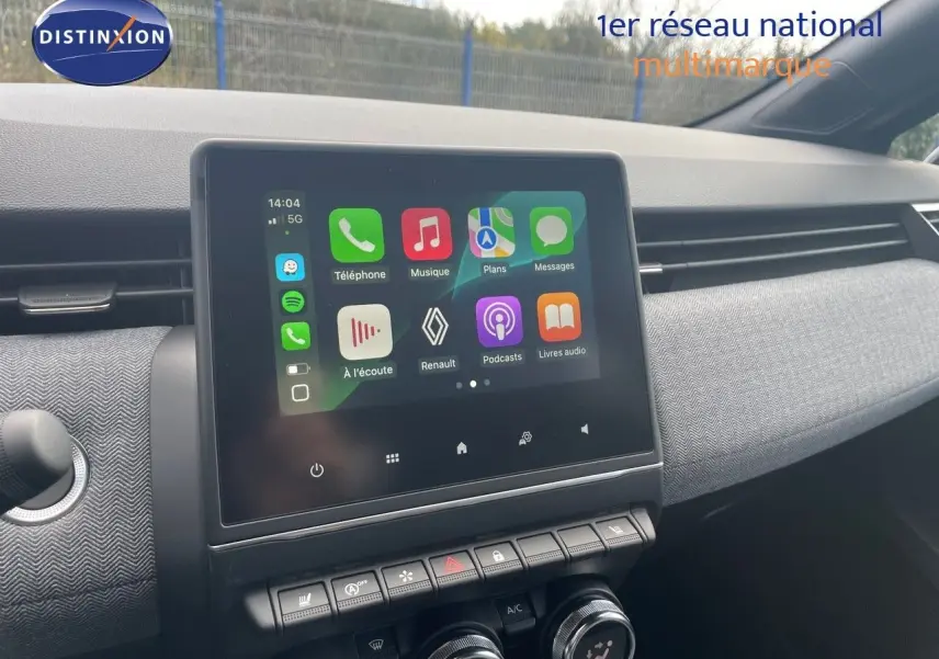 Écran tactile central allumé avec interface Renault, tableau de bord gris texturé, vue de l'habitacle avant droit.