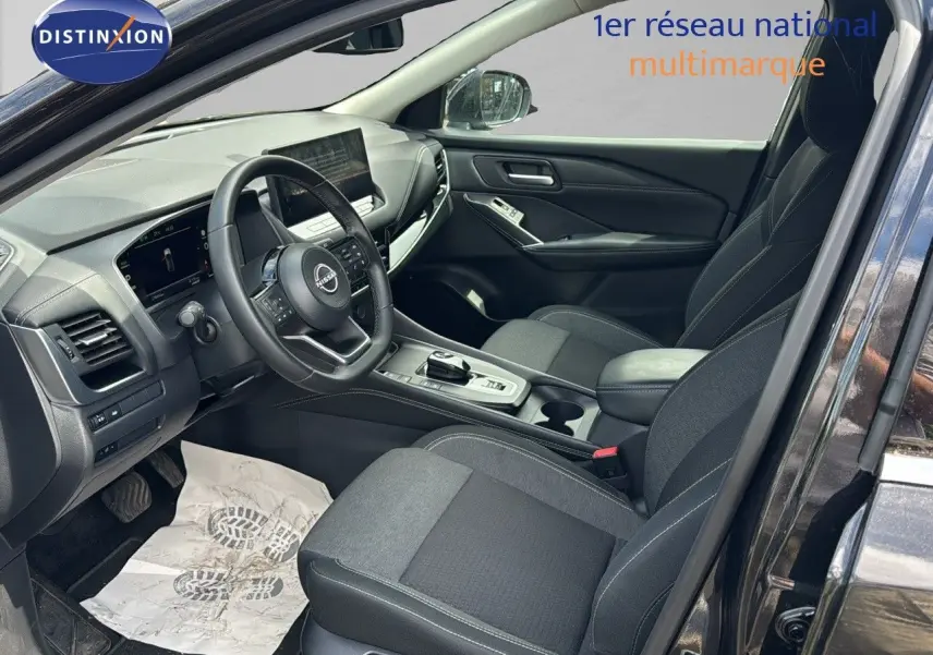 Intérieur avant droit du Nissan Qashqai 2024 noir, avec tableau de bord moderne et sièges tissu gris.