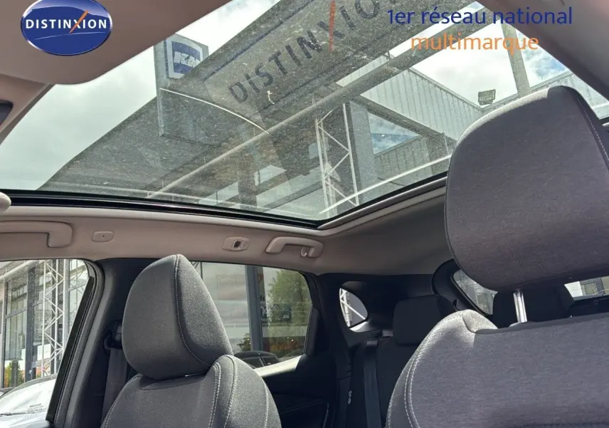 Vue intérieure du Nissan Qashqai 2024 noir, montrant les sièges avant et le toit ouvrant panoramique en verre.