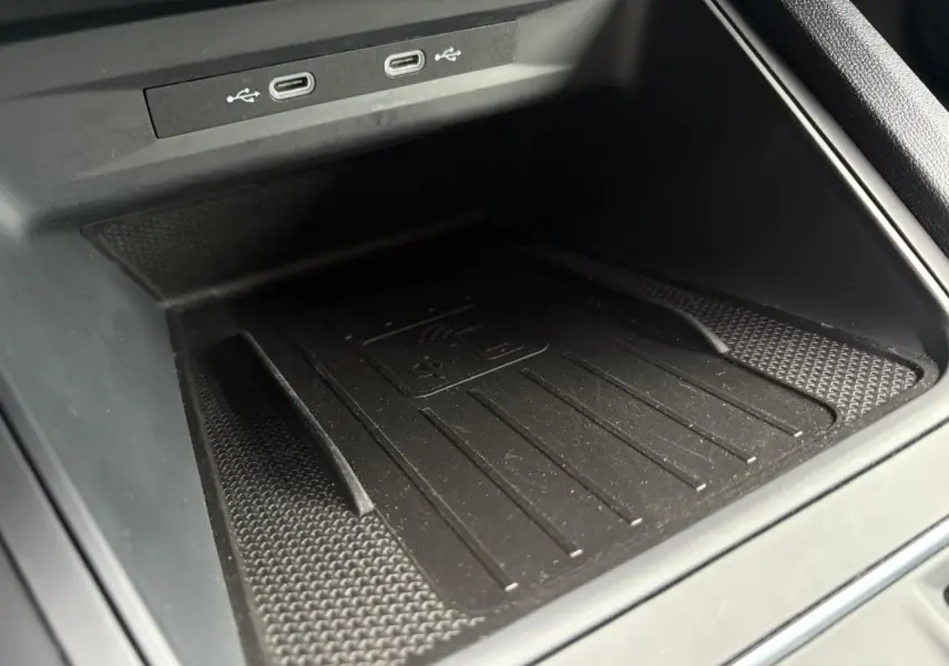 Gros plan sur la zone de recharge sans fil et ports USB-C du coffre central d'une SEAT LEON 1.5 e-TSI 150 DSG7 FR 2024.