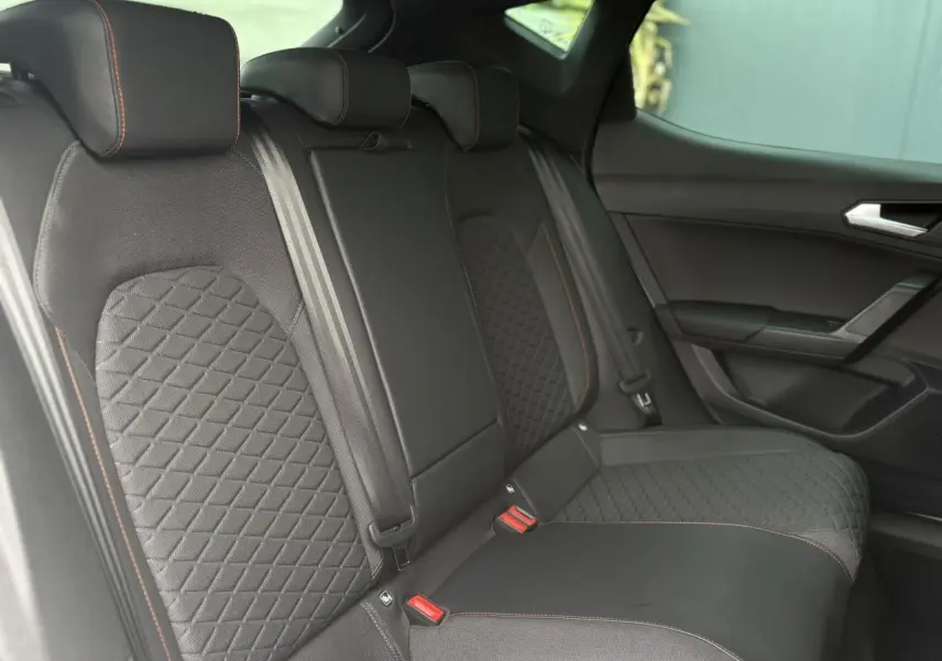 Vue intérieure des sièges arrière noirs avec surpiqûres orange de la SEAT LEON 2024 côté droit.