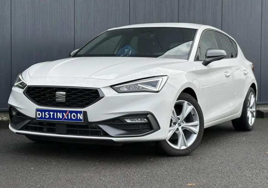 Vue 3/4 avant droite d'une SEAT Leon blanche 2024 avec jantes alliage et calandre noire distinctive.