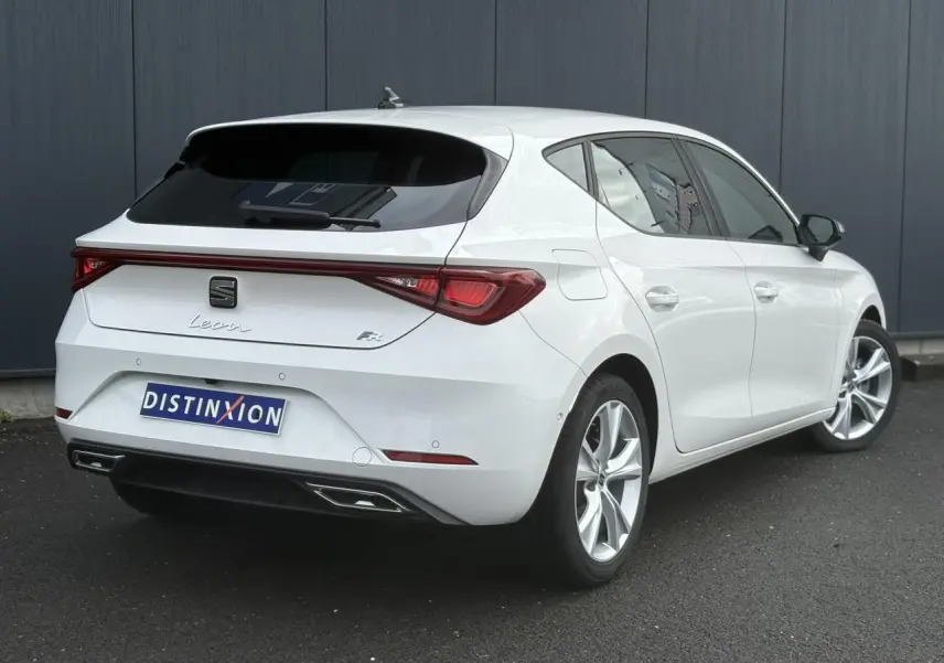 Vue 3/4 arrière droite d'une SEAT Leon FR blanche avec feux arrière LED et jantes alliage 17 pouces.