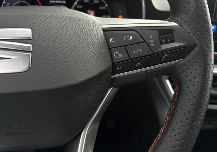 Gros plan sur le volant cuir perforé côté droit du SEAT LEON 1.5 e-TSI 150 DSG7 FR avec commandes multifonctions.