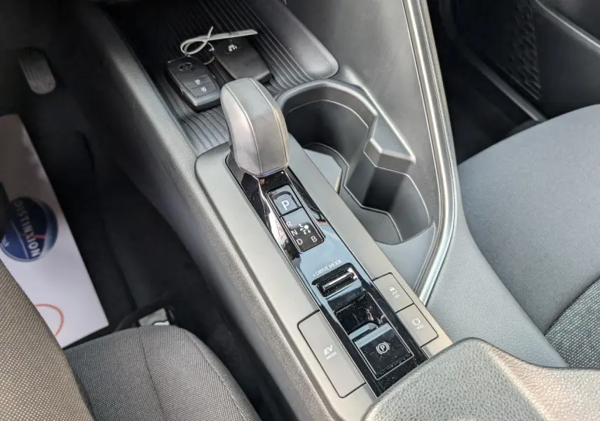 Vue rapprochée de la console centrale du Toyota C-HR 2024 hybride, avec levier de vitesse automatique et porte-gobelets.