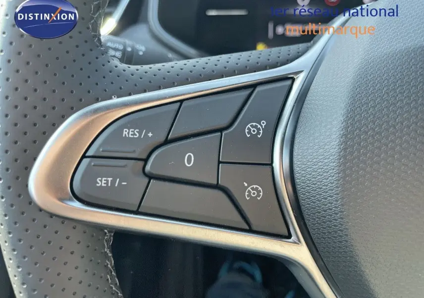 Gros plan sur les commandes du régulateur de vitesse au volant perforé de la Renault Clio TCE 90CH TECHNO noir métal 2025.