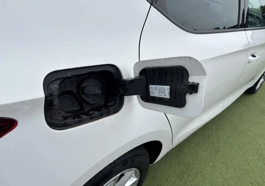 Vue latérale droite du réservoir ouvert d'une SEAT LEON blanche 2024 avec jante alliage 16 pouces visible sur sol vert.