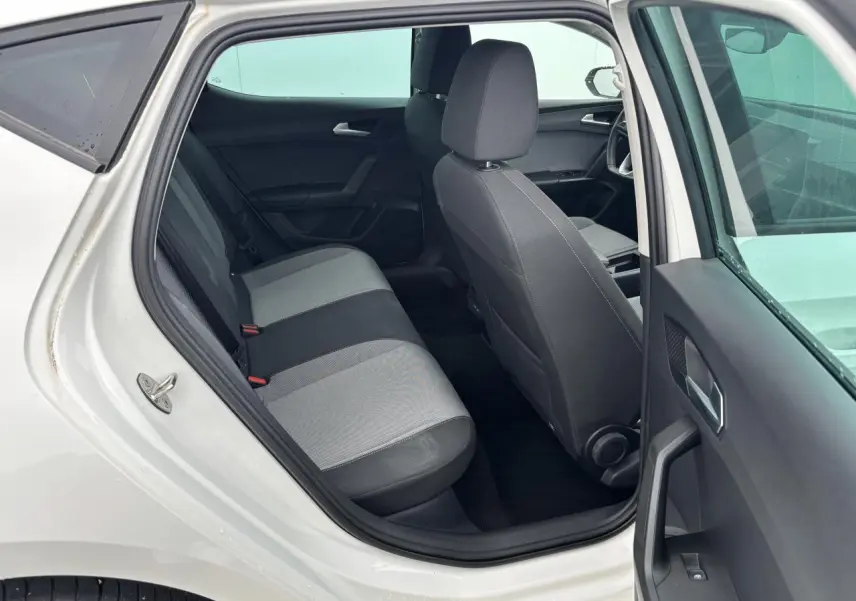 Vue intérieure côté gauche arrière d'une SEAT LEON blanche 2024, montrant les sièges arrière bicolores et la porte ouverte.