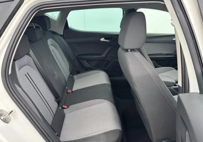 Vue intérieure côté gauche montrant la banquette arrière bicolore grise et noire d'une SEAT LEON blanche 2024.