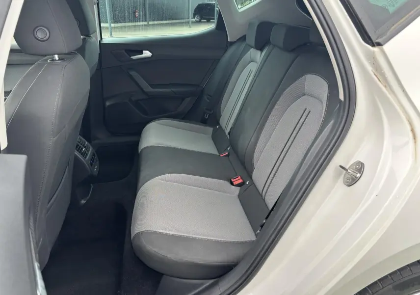 Vue côté droit arrière du siège arrière bi-ton gris et noir d'une SEAT LEON blanche 2024 avec porte ouverte.