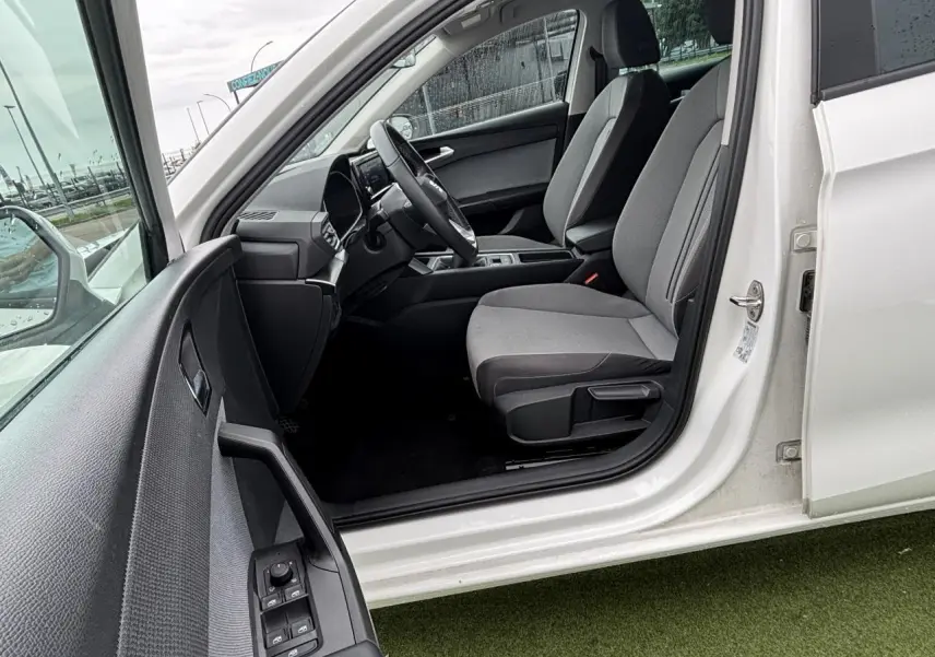 Vue côté gauche intérieur d'une SEAT LEON blanche 2024, montrant les sièges avant et le tableau de bord moderne.