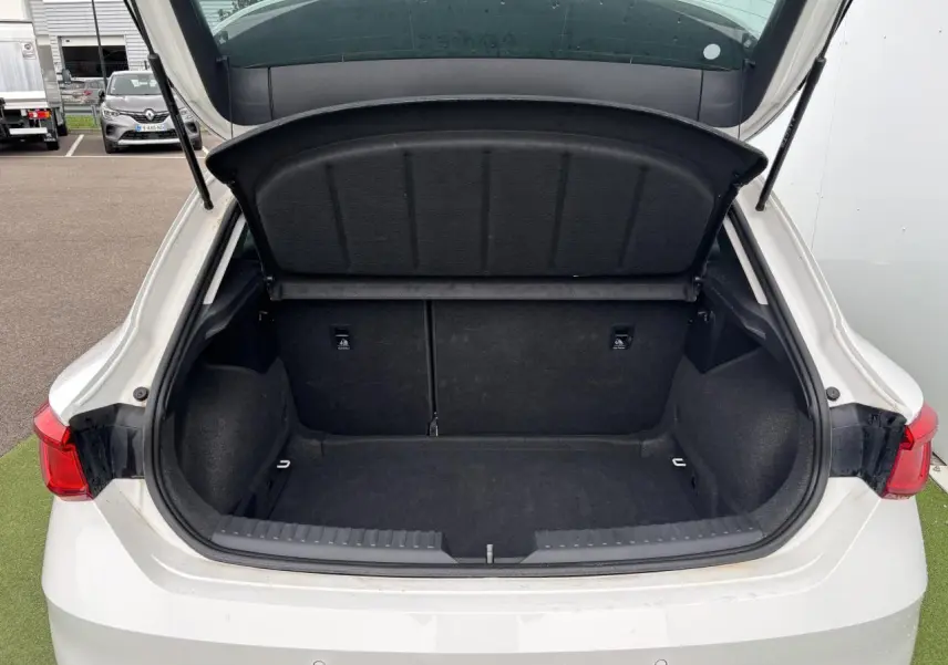 Coffre ouvert vu de l'arrière d'une SEAT LEON blanche 2024, montrant un espace de chargement propre et spacieux.