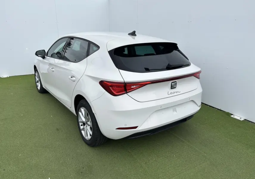 SEAT Leon blanc vue 3/4 arrière droit, avec feux arrière reliés par une bande lumineuse rouge.