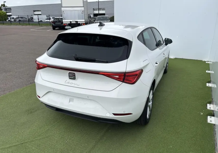 Vue 3/4 arrière droite d'une SEAT Leon blanche 2024 avec feux arrière LED et jantes alliage 16 pouces.